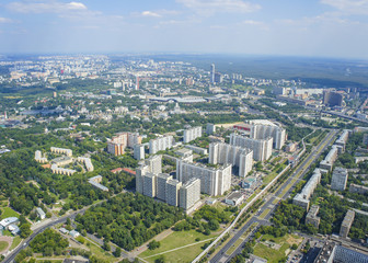 Top view of big city in the summer. Urban panorama of cityscape and blue sky, groups of buildings.