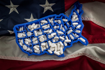 Healthcare, opioid epidemic and drug abuse concept with the map of USA filled with oxycodone and hydrocodone pharmaceutical pills on the American flag