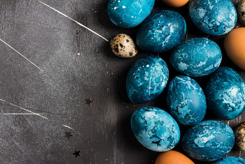 Easter eggs painted by hand in blue color on dark background