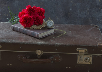 composition about memories: the time of war, on a trunk suitcase, clocks, carnations and a book