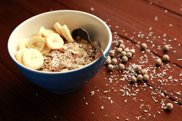 Healthy breakfast. Granola bowl with banana, raisins and nuts. And a glass of milk on the wooden background. Close up photo. Sweet vegan dish. Morning oatmeal closeup.