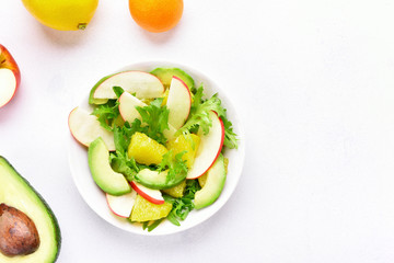Fruit vegetable salad with red apples, avocado, orange slices