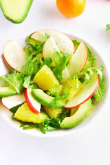 Salad with red apples, avocado, orange slices