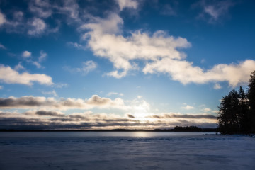 View of the winter lake under the snow and sunset