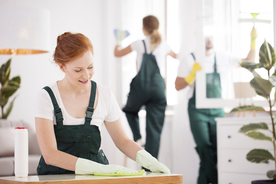 Smiling cleaning lady wiping table