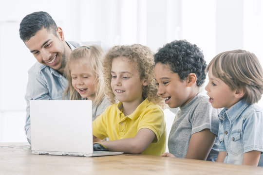 Happy kids programming on laptop