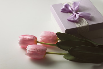 Three Pink Tulips and a Gift Box On The White Background. Artificial flowers. Copy space