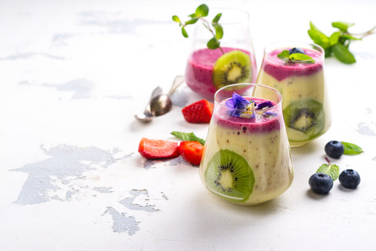 Colorful detox layered smoothie with natural edible flowers, berries and mint