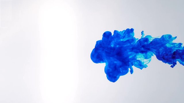 Blue ink dropped in water on white background