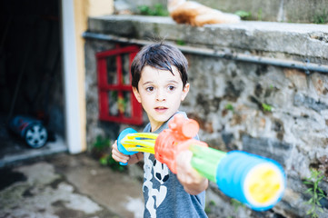 children play in the garden with guns and water rifles on a sunny summer day
