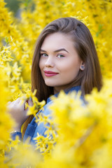 Close up portrait of young beautiful woman in the middle of yellow flower field in bloom - cheerful young girl alone in nature