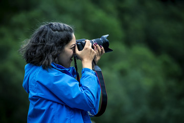 Young woman in blue jacket and curly hair is taking a picture, close up, soft focus, Norway.