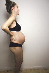 Obraz premium beautiful pregnant young woman posing in lingerie and showing her belly