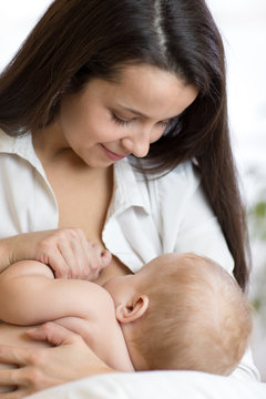 Young mom holding her newborn child. Mom nursing baby. Pretty woman breast feeding kid.