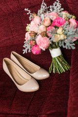 Female fashion beige wedding shoes in focus with elegant bride's bouquet in pastel tones out of focus. Wedding