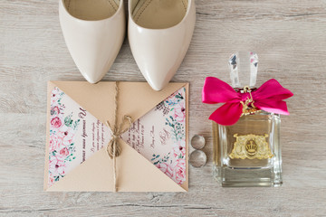 Wedding accessories: bridal shoes, rings, invitation, perfume. Wedding details in beige shades. View from above