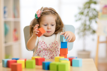 cute child playing with block toys in day care center