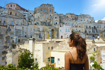 Back view of young woman traveling and discovering an old town of South Europe. Traveler girl...