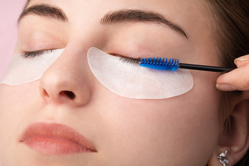 Beautiful young woman with cotton pads around her eyes during eyelash extensions