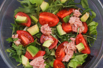 Italian Salad from Tomatoes, Rucola, Grated parmesan Cheese, Olive Oil, Olives, Tuna, on White Plate. Top View.