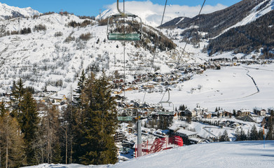 Chairlift at Italian ski area on snow covered Alps and pine trees