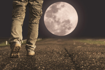 A man and sneaker shoes walking under full moon at night