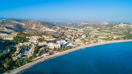 Fototapeta na wymiar Aerial bird's eye view of Pissouri bay, a village settlement between Limassol and Paphos in Cyprus. Panoramic view of the coast, beach, hotel, resort, hills, plain and building developments from above