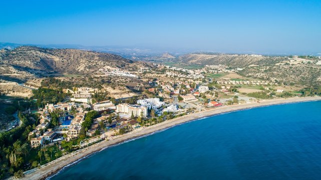 Aerial bird's eye view of Pissouri bay, a village settlement between Limassol and Paphos in Cyprus. Panoramic view of the coast, beach, hotel, resort, hills, plain and building developments from above