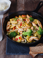 Fried chicken with potatoes and vegetables in a frying pan. Potatoes with meat in a rustic. Traditional European cuisine.