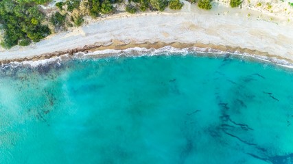 Aerial bird's eye view of Pissouri bay, a village settlement between Limassol and Paphos in Cyprus. The shore, beach with white sand pebbles and crystal clear clean blue water on the shore from above.