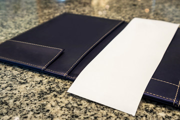 Blank empty white paper in restaurant payment billing receipt folder on granite table