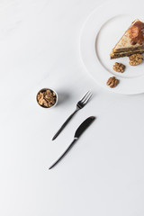 Top view of cake on plate, walnuts and cutlery
