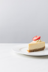 Cheesecake with piece of fresh strawberry on white plate