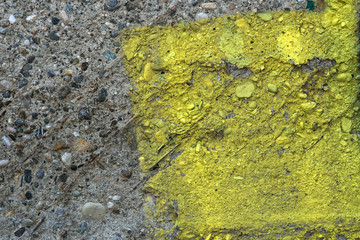 Old grunge cement with pebbles and scraps of yellow paint