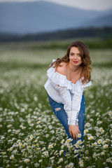 Fototapeta premium Beautiful happy smiling woman on the camomile field is wearing white dress, spring time