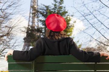 junge Frau mit einer Baskenmütze und dem Eiffelturm
