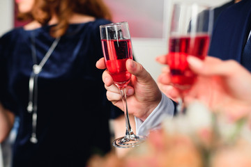 glass of red champagne in the hand of a man in a suit at the festival close-up. Symbolizes success and good fortune