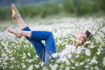 Beautiful happy smiling woman on the camomile field is wearing white dress, spring time