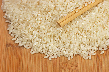 raw rice and chopsticks on bamboo board