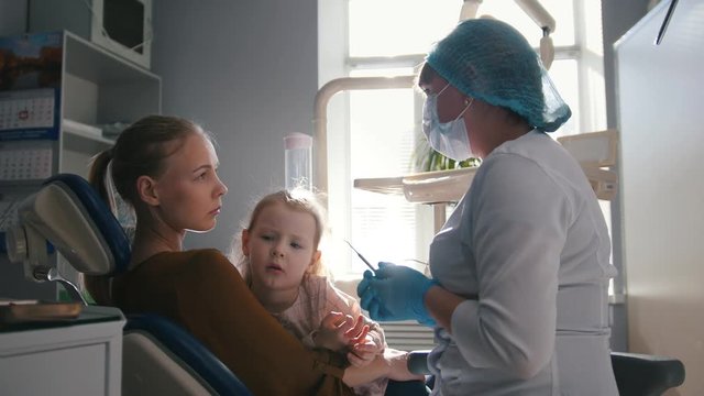 Girl, her mom and the dentist in the dental office, the stomatologist consulting with a special toy