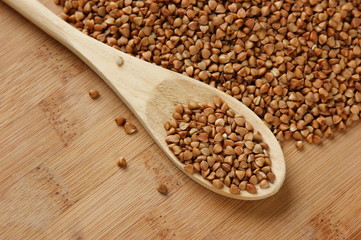 Fototapeta premium buckwheat groats and wooden spoon on the kitchen table