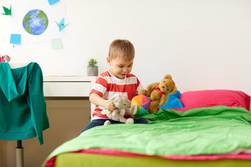 happy little boy playing with plush toys at home