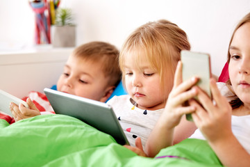 little kids with tablet pc in bed at home