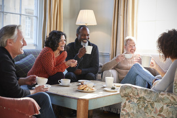 Group Of Middle Aged Friends Meeting Around Table In Coffee Shop