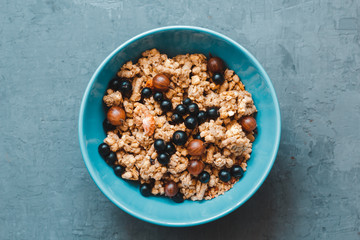 granola or flakes with berries of black currant and gooseberry in a pink plate on a white background. top view. Healthy vegetarian food. close-up