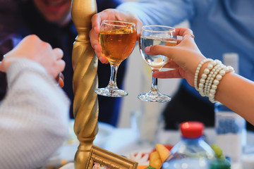 glasses of white wine in the hands of people at the festive table in the restaurant