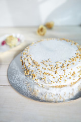 light diet layered biscuit with curd cream and cherry. cake covered with curd cream and garnished with dried roses on the white wooden background