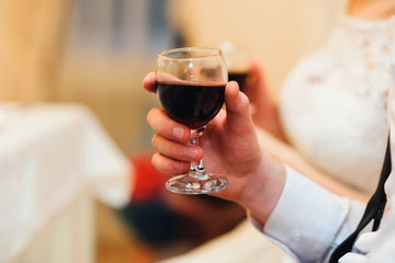 glass of red wine in the hand of a man close-up with a blurred background