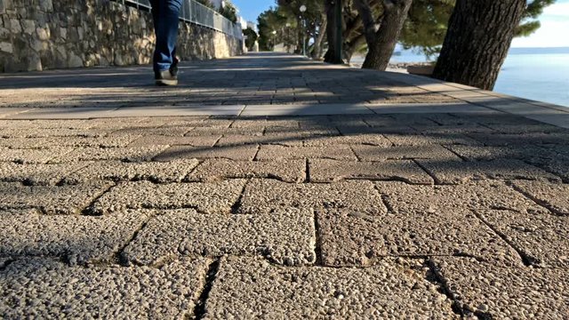Man in casual clothes walk on walking trail close to the sea slow motion