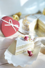 light diet layered biscuit with curd cream and cherry. cake covered with curd cream and garnished with dried roses on the white wooden background